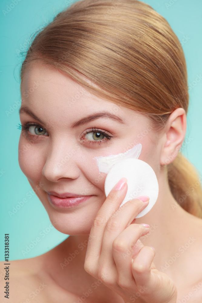 Woman removing makeup with cream and cotton pad Woman removing makeup with cream and cotton pad