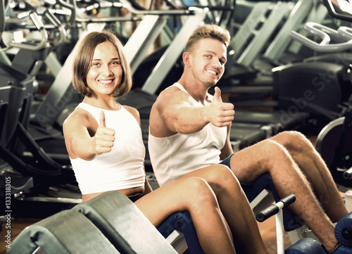 man and woman making sit ups together using machine in gym