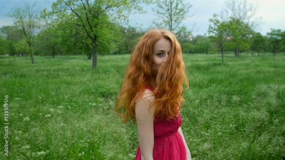 Beautiful, attractive young red-haired girl running on the grass in the forest Beautiful, attractive young red-haired girl running on the grass in the forest