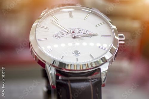 Close up shot of a luxury men watch. Lens flare in background.