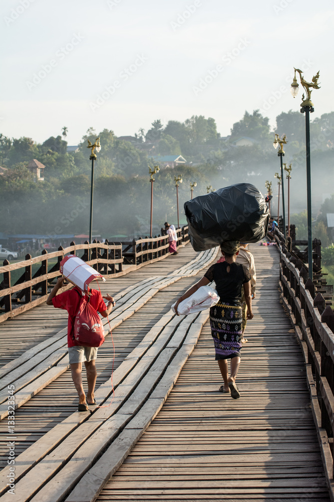 Myanmar woman worker on wooden bridge.(smoke background)