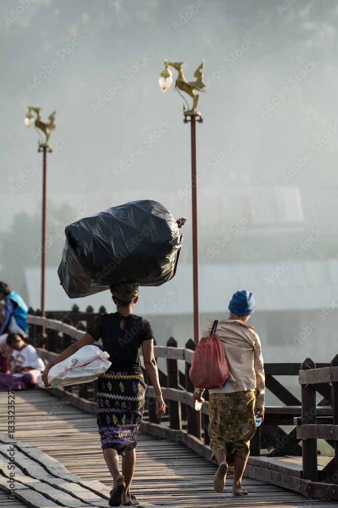 Myanmar woman worker on wooden bridge.(smoke background)