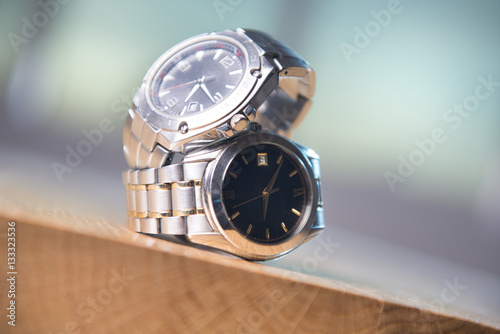 Pair of stainless steel watches on the wooden table.