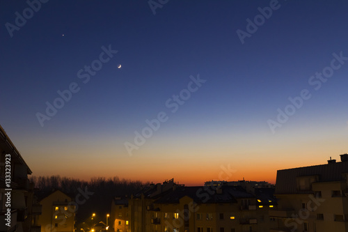 Fotografija moon and star in the evening over estate houses, falling asleep in the city