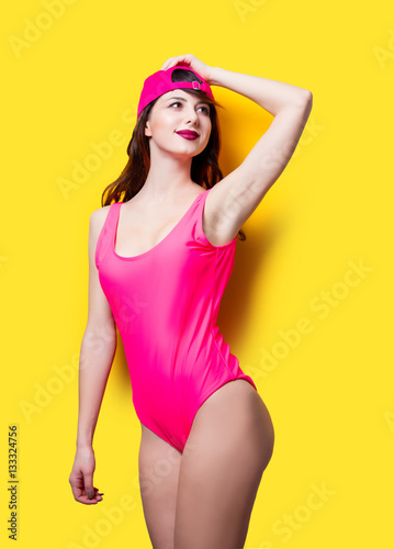 Elegant brunette woman in pink swimsuit and fashion cap. Sexy la