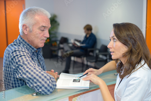 Obraz na plátne Medical secretary showing booklet to patient