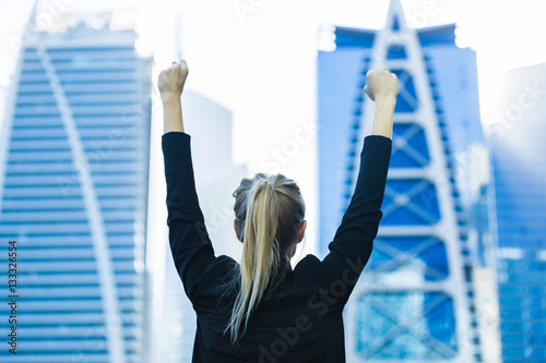 Business success - Celebrating businesswoman overlooking the city center high-rises.