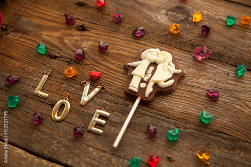 Valentine's day chocolate candy with kissing couple and letters on wooden background.