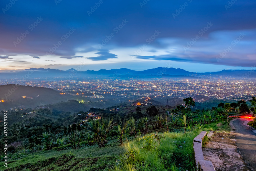 Hills and beautiful city light at night, seen faraway from top of the hilll, also showing shadow of mountain in the background, captured in Bandung, Indonesia