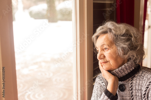 Canvastavla Senior woman looking through window