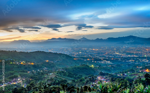 Hills and beautiful city light at night, seen faraway from top of the hilll, also showing shadow of mountain in the background, captured in Bandung, Indonesia