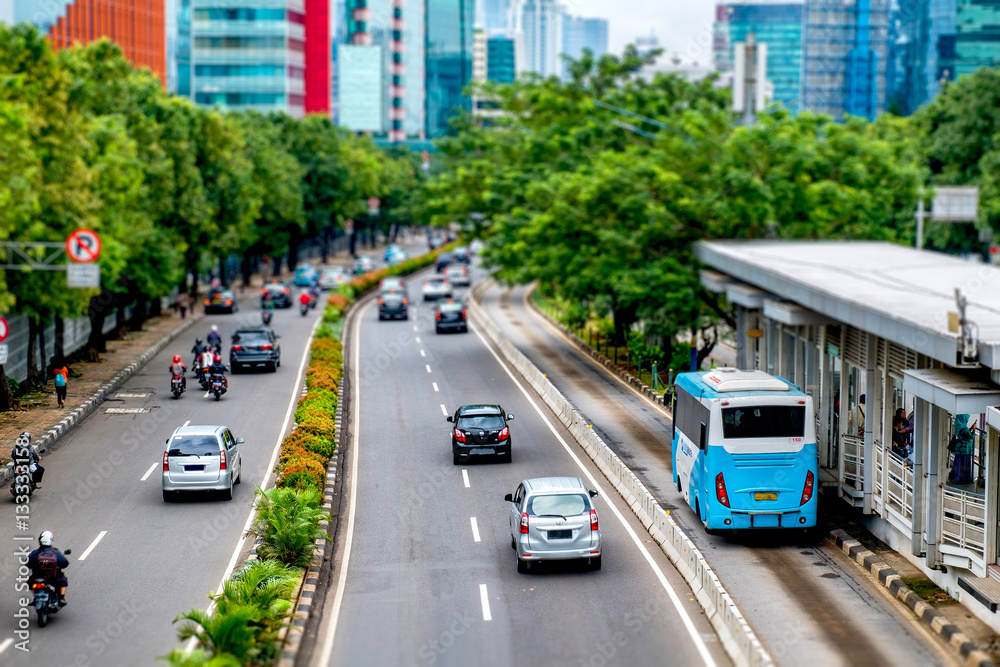 Fototapeta premium Public transport bus stopped in bus stop, waiting until passenger get in, in busy street at Jakarta, Indonesia.