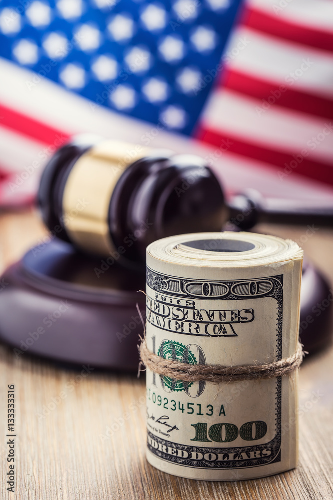Judge's hammer gavel. Justice dollars banknotes and usa flag in the background. Court gavel and rolled banknotes. Still life of a bribery, corruption in the US judicial system.