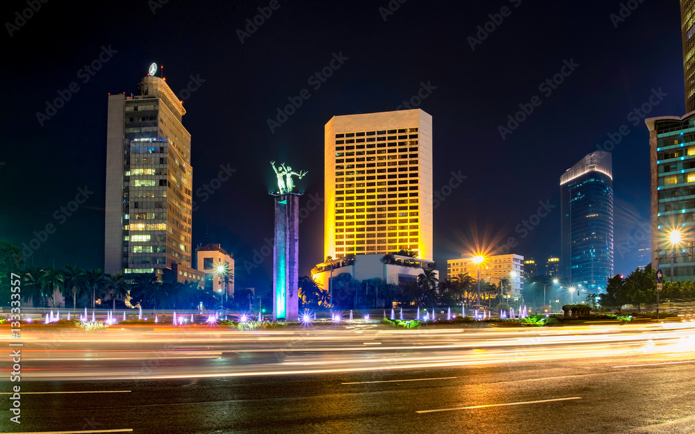 Selamat Datang monument in front of Jakarta's skyscrapers. Behind busy traffic in Bundaran Hotel Indonesia, or Hotel Indonesia roundabout, Sudirman Street,  Jakarta. Urban Skyline, Building Exterior, 