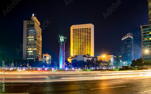 Selamat Datang monument in front of Jakarta s skyscrapers. Behind busy traffic in Bundaran Hotel Indonesia  or Hotel Indonesia roundabout  Sudirman Street   Jakarta. Urban Skyline  Building Exterior  
