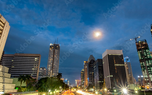 Iconic skyline and heavy traffic in Sudirman Street  Jakarta  Indonesia at dusk  showing light trail  of busy traffic and iconic skyscrapers in Jakarta  iluminated by moon light.  Urban Skyline  Build