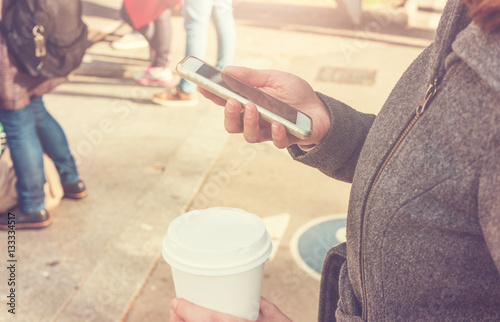 smartphone and coffee in womans hand