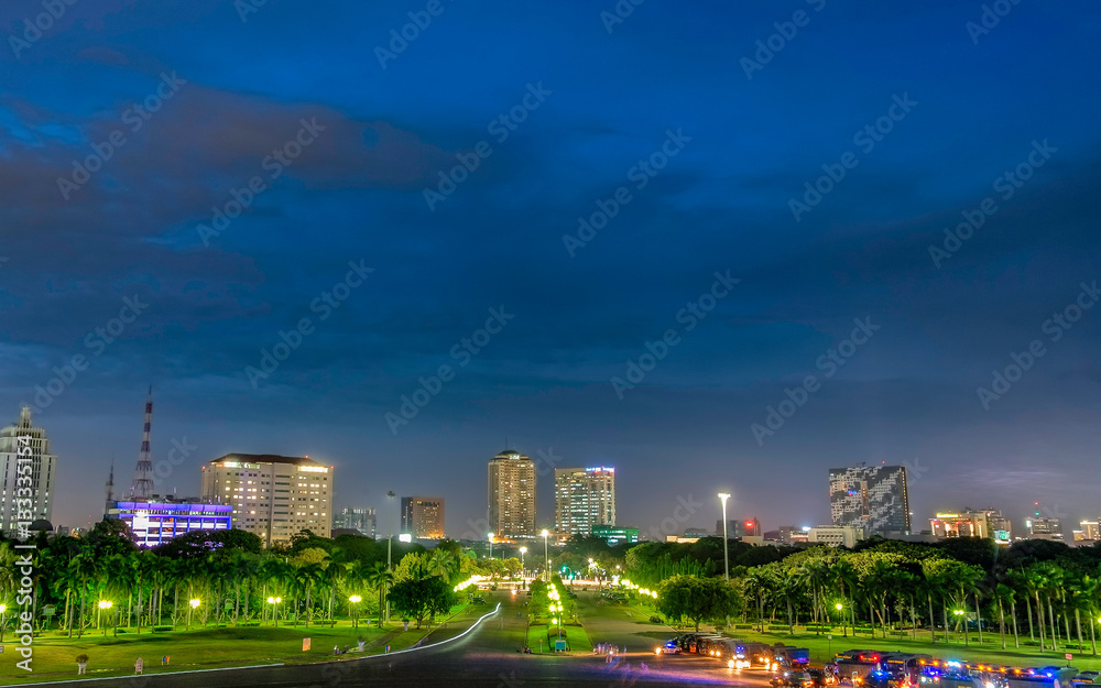 View of skyscraper buildings seen from city park, captured from Monumen Nasional (Monas), Jakarta Indonesia. This skyline captured at dusk or blue hour