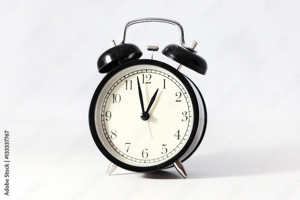 Black alarm clock. Retro clock on the white table. Cream dial