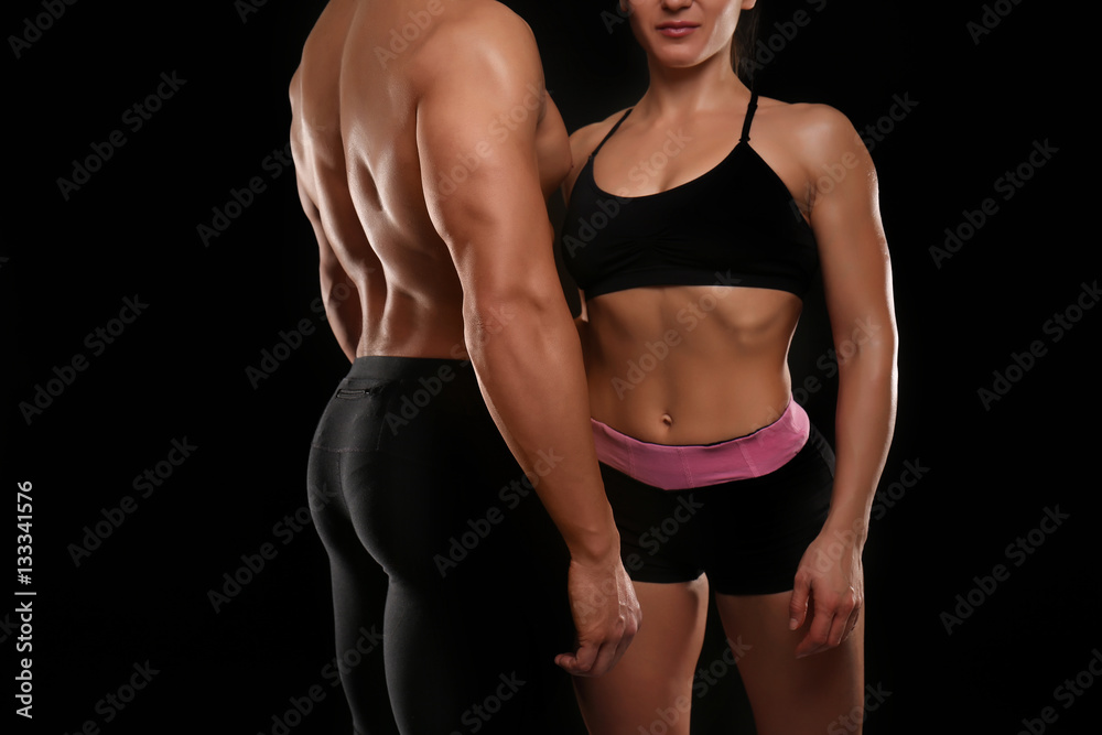 Fototapeta premium Sporty young couple on black background, closeup