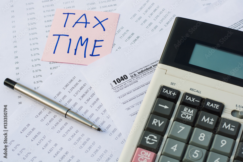 Tax Time written on pink sticker note with on U.S. tax form Tax Time written on pink sticker note with on U.S. tax form