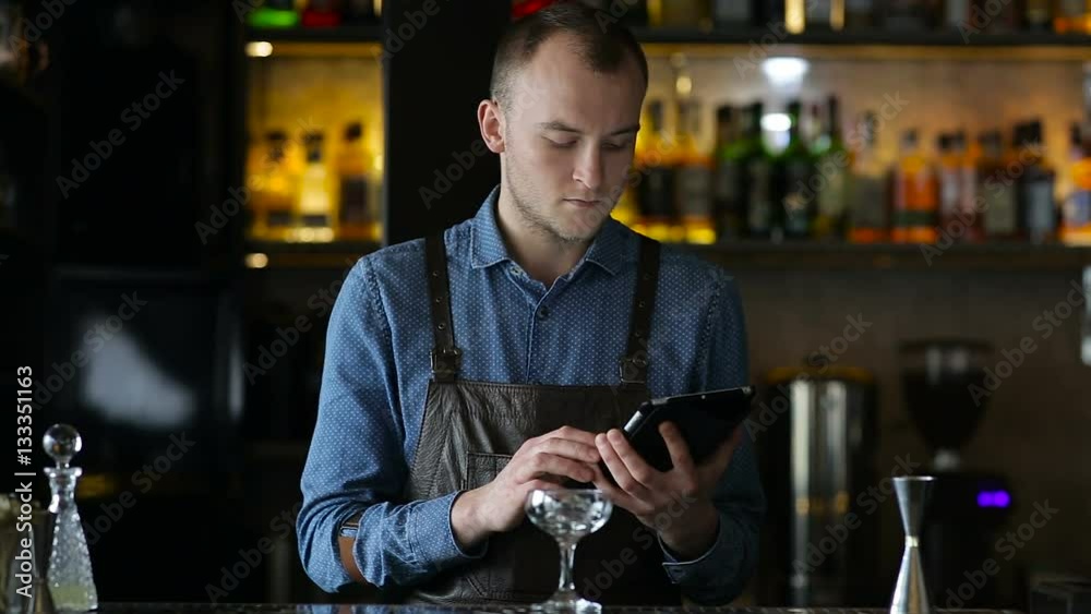Young bartender exploring new cocktails using tablet Young bartender exploring new cocktails using tablet