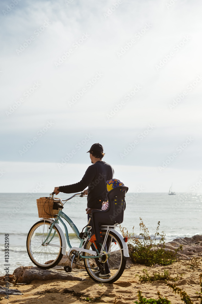 Fototapeta premium Defocused silhouette of child and father with bike on a beach natural outdoor. Travel vacation background