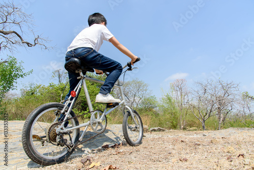 Fototapeta Naklejka Na Ścianę i Meble -  Little boy ride bicycle on the rock road.