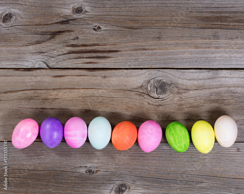 Colorful eggs for Easter holiday forming lower border on wood 