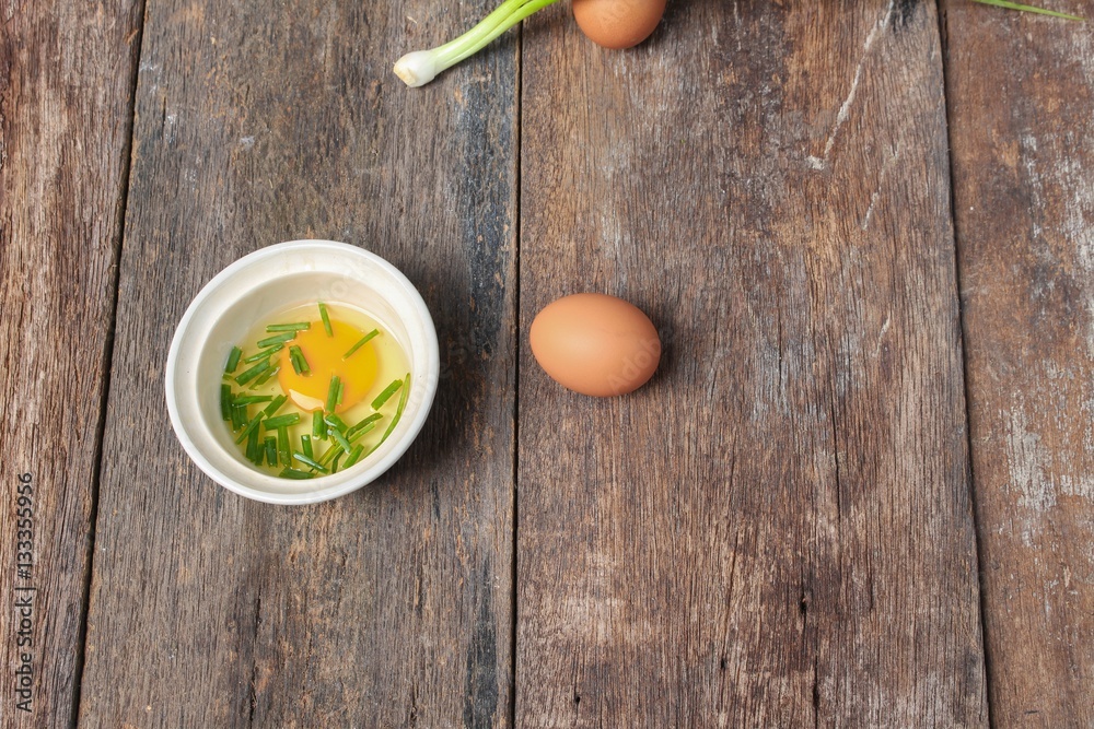 Raw egg in a bowl selective focus and onion on wooden table Raw egg in a bowl selective focus and onion on wooden table