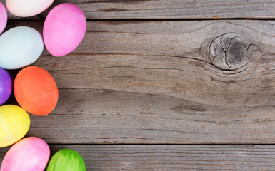 Colorful eggs for Easter holiday forming left hand border on wood