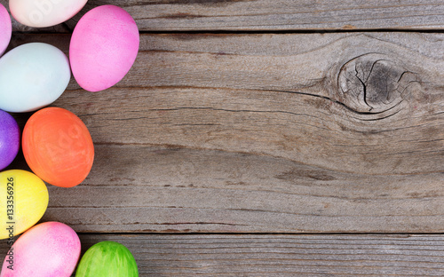 Photography Colorful eggs for Easter holiday forming left hand border on wood