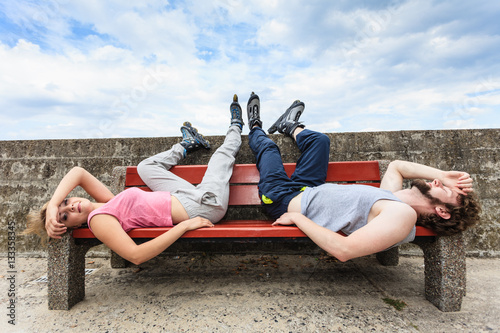 Young tired people friends relaxing on bench.