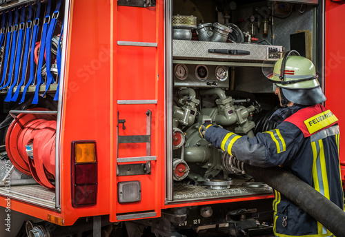 HDR - Feuerwehrmann bedient im Einsatz einen Löschschlauch am Feuerwehrfahrzeug