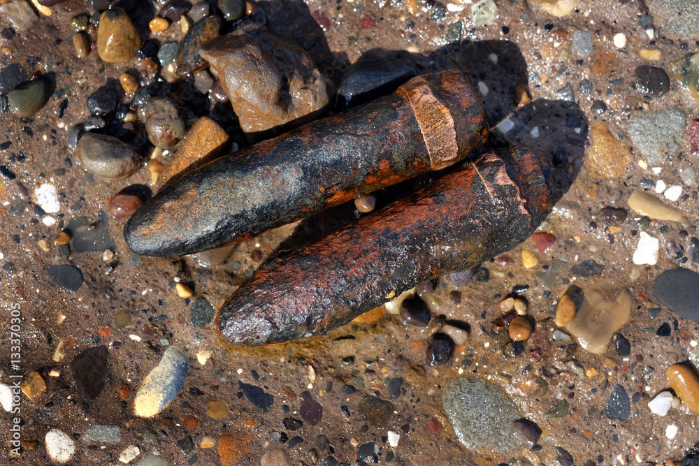 Spent twenty millimeter canon shells in sand on a UK east coast beach near world war two practice firing ranges. Spent twenty millimeter canon shells in sand on a UK east coast beach near world war two practice firing ranges.