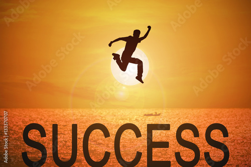 Silhouette of young man jumping over the success words with beautiful sunset at the sea background, concept for success and victory in business.