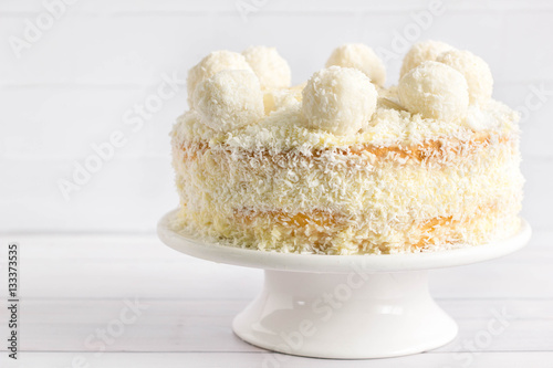 Coconut cake with healthy balls on top, white background. photo