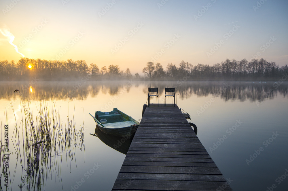 boat moored to a wooden bridge, a beautiful sunrise over the lak