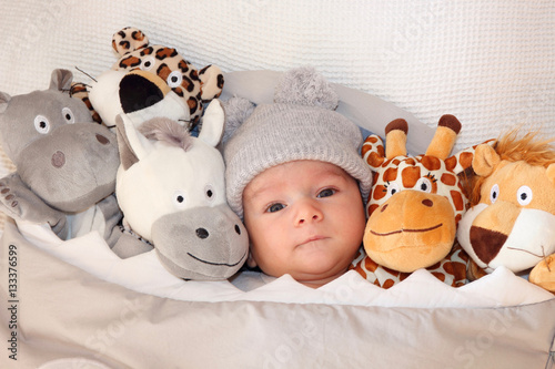 Photography Sweet little baby lying on the bed surrounded of cute safari stuffed animals