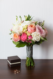 Wedding bouquet and delicate little brown box with wedding rings on a wooden surface