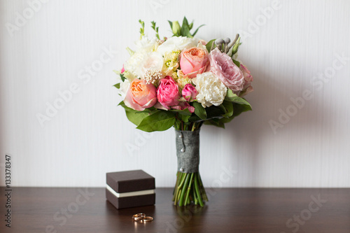 Wedding bouquet and delicate little brown box with wedding rings on a wooden surface © Olga Mishyna