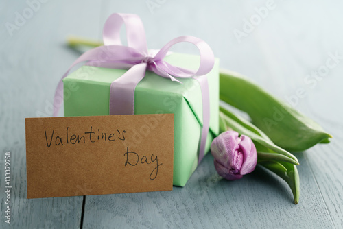 tulip flower with green gift box and paper card on blue wood table for valentines day, romantic photo