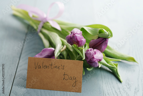 bouquet of purple tulips on wood table with paper card for valentines day, shallow dof