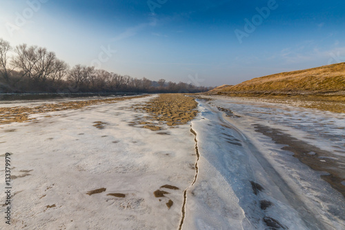 Winter scenery, with frozen river and ice covered sand dunes, on a cold sunny day