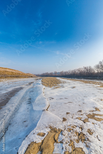 Winter scenery, with frozen river and ice covered sand dunes, on a cold sunny day