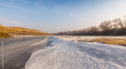 Winter scenery, with frozen river and ice covered sand dunes, on a cold sunny day