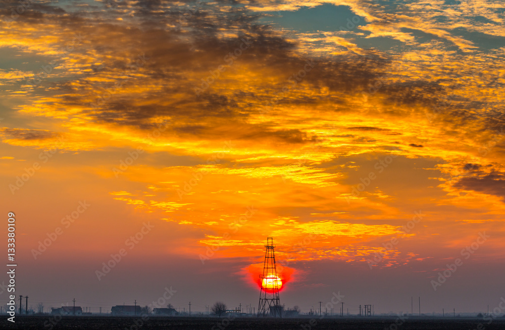 Obsolete oil and gas rig profiled on dramatic evening sky