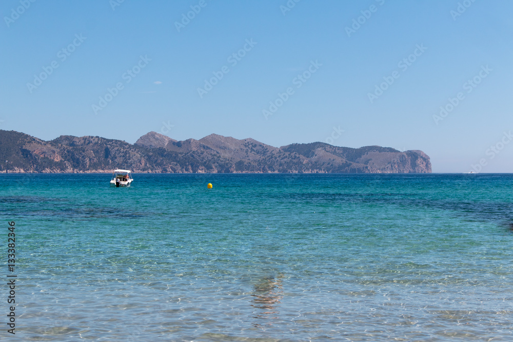 Boat on the water of a Mallorca beach with turquoise water and bright blue sky