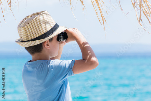 Boy on summer tropical beach with binoculars