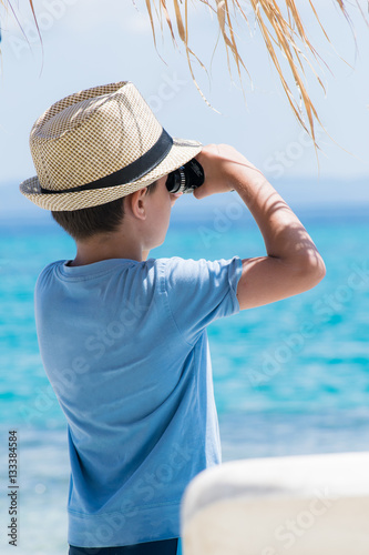 Boy on summer tropical beach with binoculars